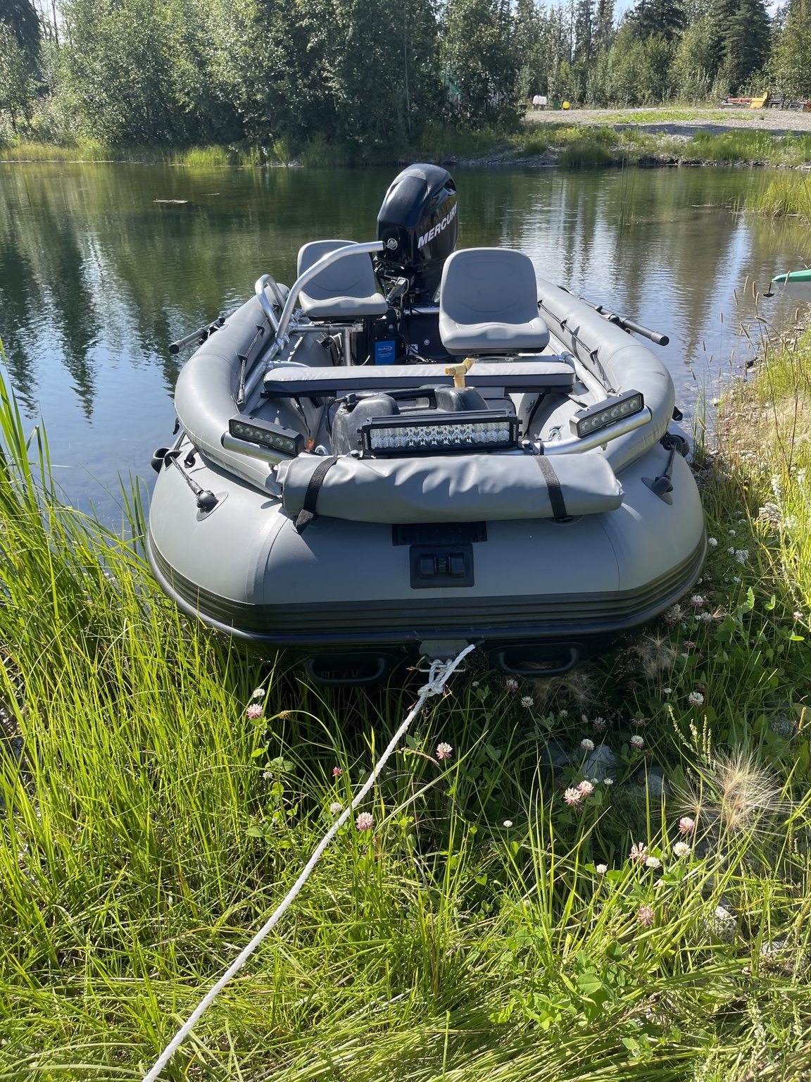 Fully rigged gray inflatable riverboat with LED light bars, swivel seats, and a Mercury outboard on the water